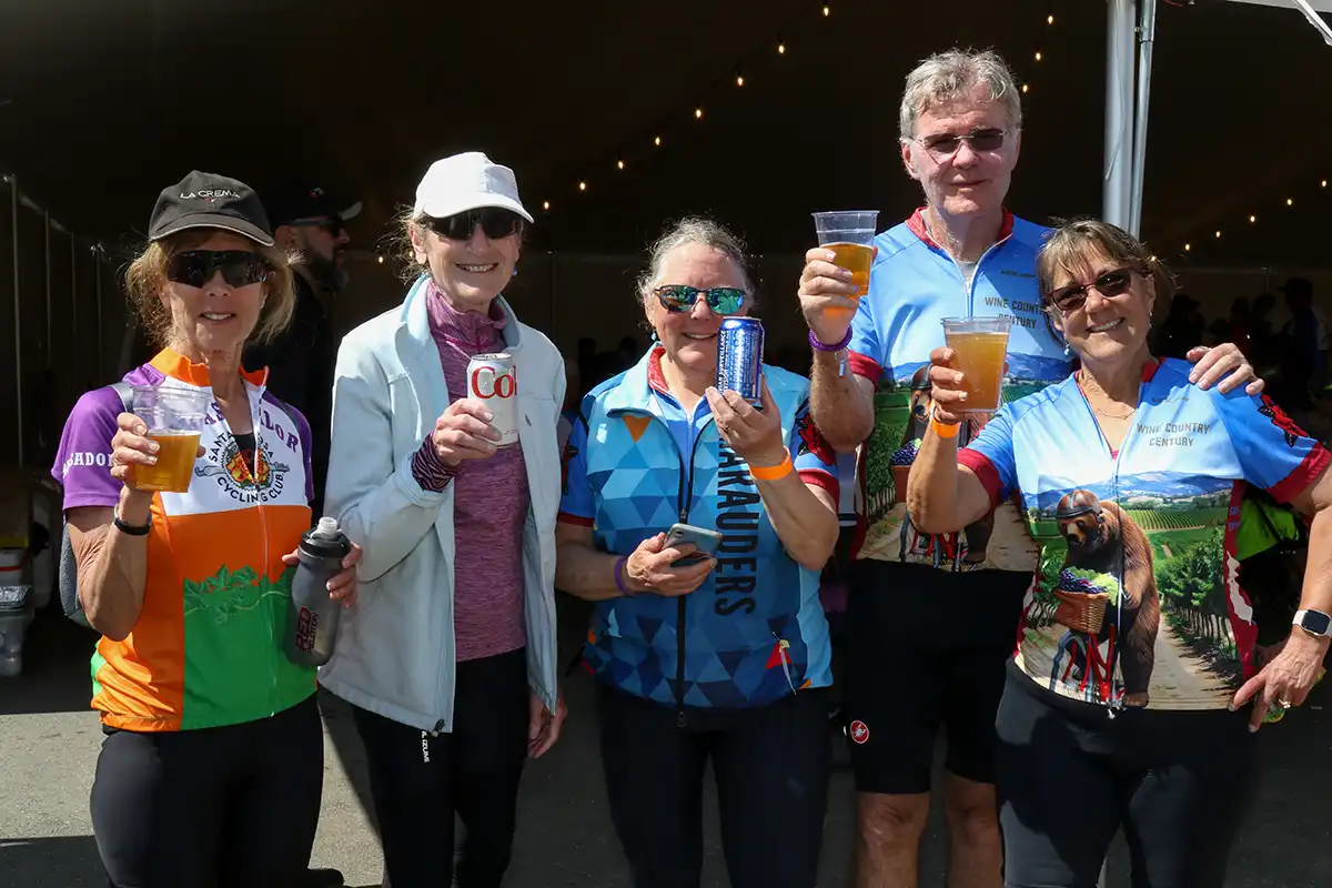 Group of cyclists celebrating with drinks.